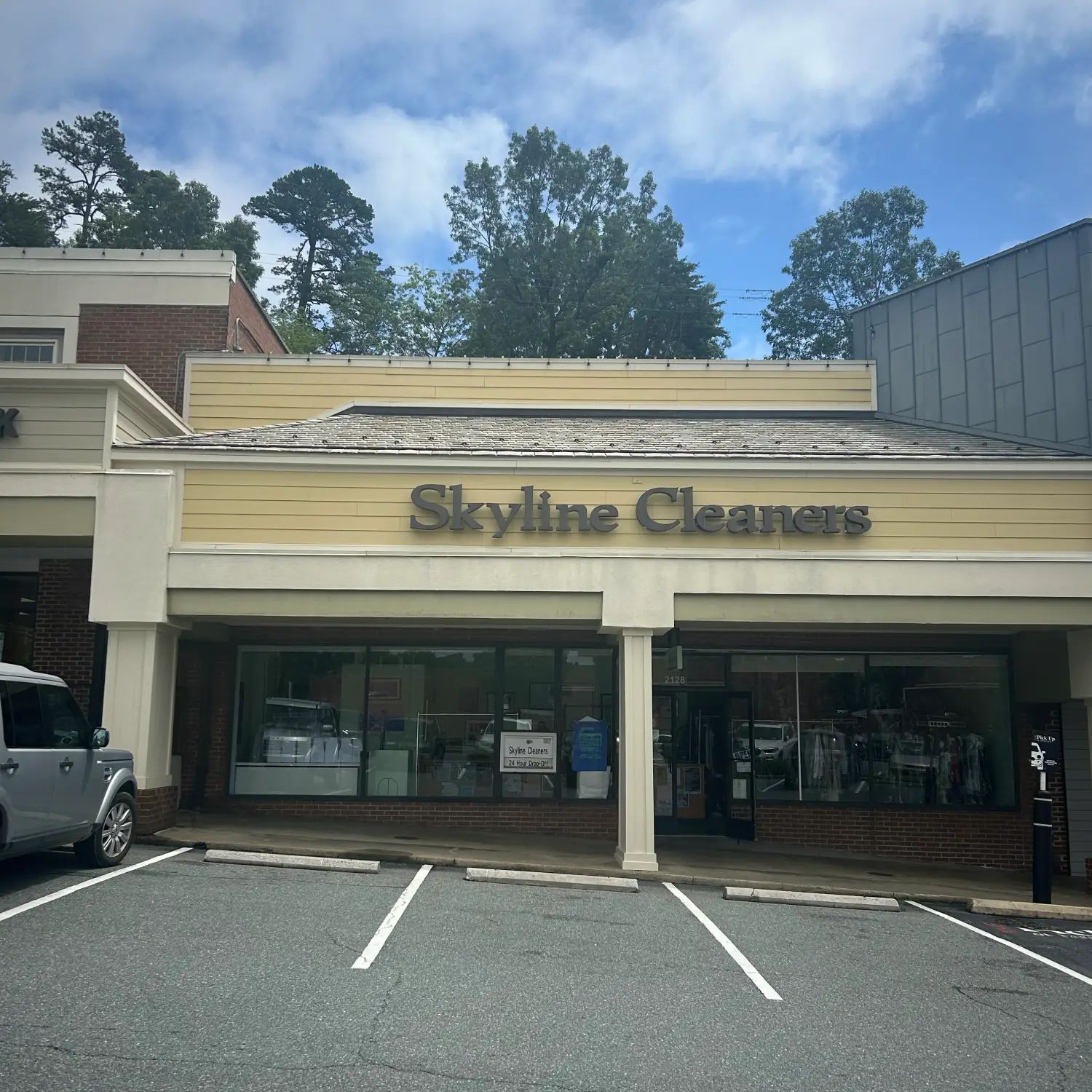 Exterior view of Skyline Cleaners, a dry cleaning business, featuring a large front window and signage against a partly cloudy sky.