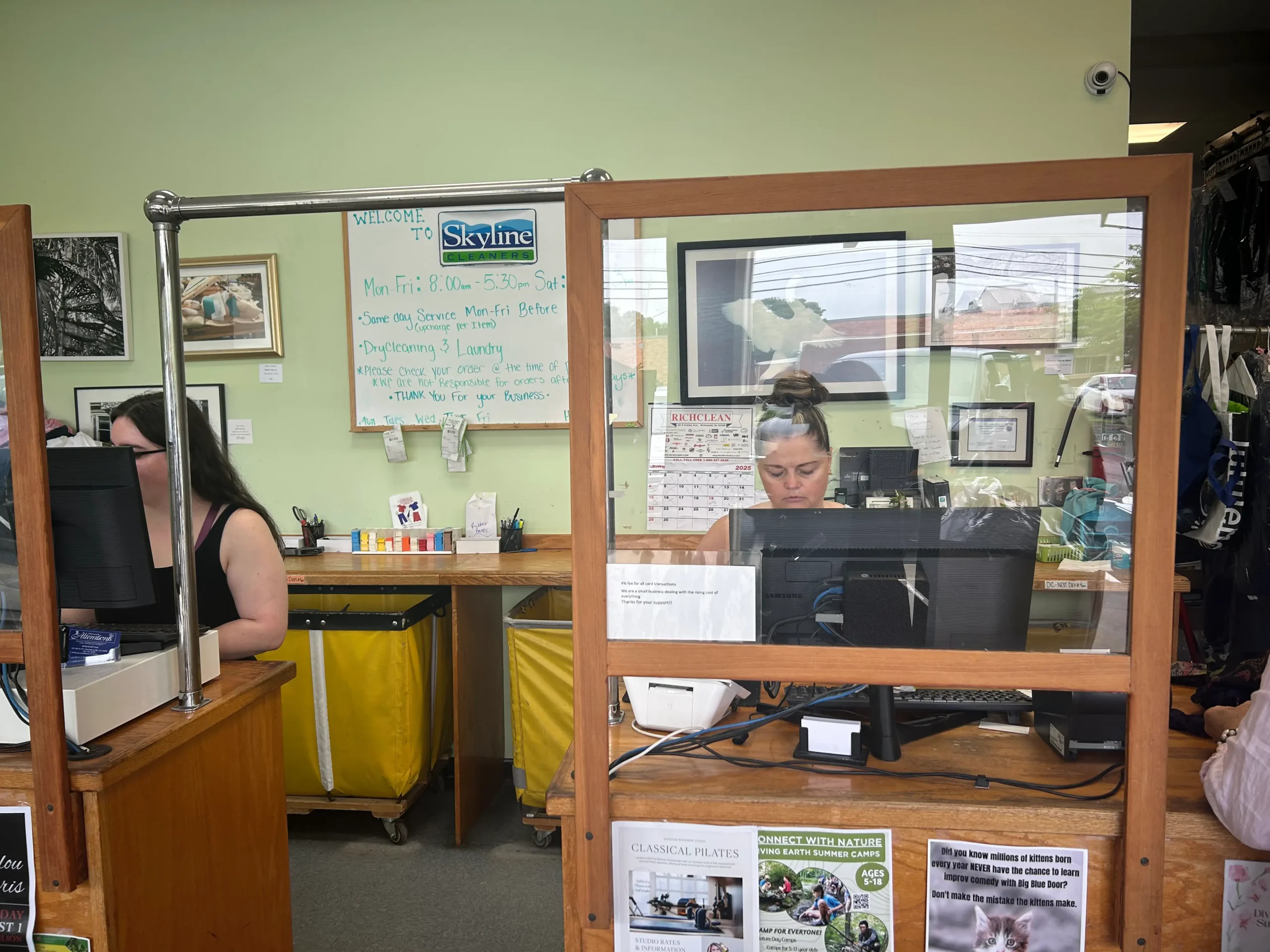 A clean and organized reception area of Skyline Cleaners featuring a computer, calendar, and informative signs on a green wall.